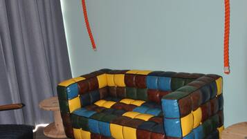 Un sofá colorido y de estilo patchwork con base de madera y un columpio suspendido del techo.