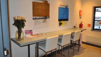 A long table with four chairs, a vase with flowers, and informational posters on the wall.