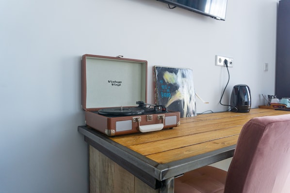 A vintage vinyl record player on a wooden table with a wall-mounted TV above it.