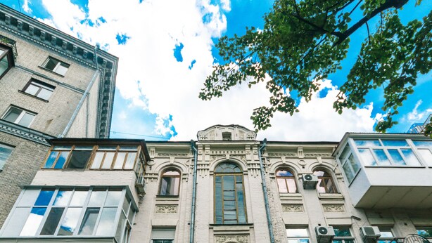 A multi-story building with a classic architectural style, featuring a central entrance with a black door, multiple windows, and balconies. - Guest House on Bessarabska Square (Kyiv)