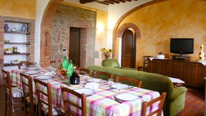 A dining area with a table set for four, a green sofa, and a television in the background.