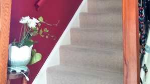 Una escalera con barandilla de madera y pared roja.