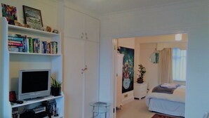 Habitación bien iluminada con televisión, estantería y cama con vistas al exterior.