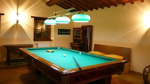 Ein Billardtisch mit Holzrahmen und grüner Spielvliesdecke, eine Holzbank und ein Holzschrank mit Spiegel.