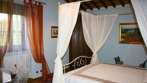 Ein Schlafzimmer mit Himmelbett, Holzbalkendecke und einem Bild an der Wand.