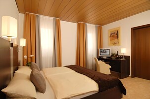 Quarto de hotel com uma cama, uma escrivaninha, uma televisão e um quadro na parede.