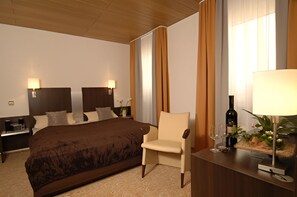 A hotel room with a large bed, a chair, a desk, and a lamp. - Garni-Hotel Adler (Ostfildern)