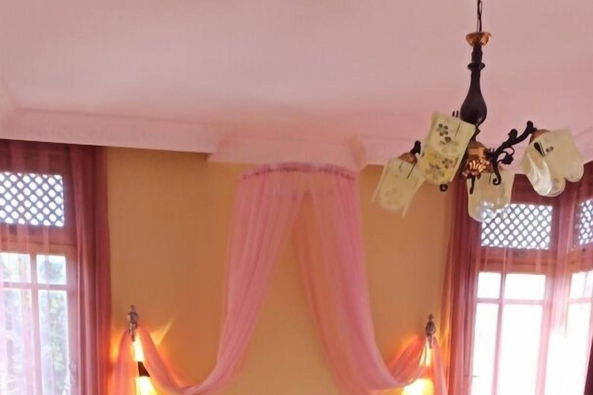 Un dormitorio con cabecera de madera, una cama con colcha blanca y burdeos, y dos lámparas de noche.