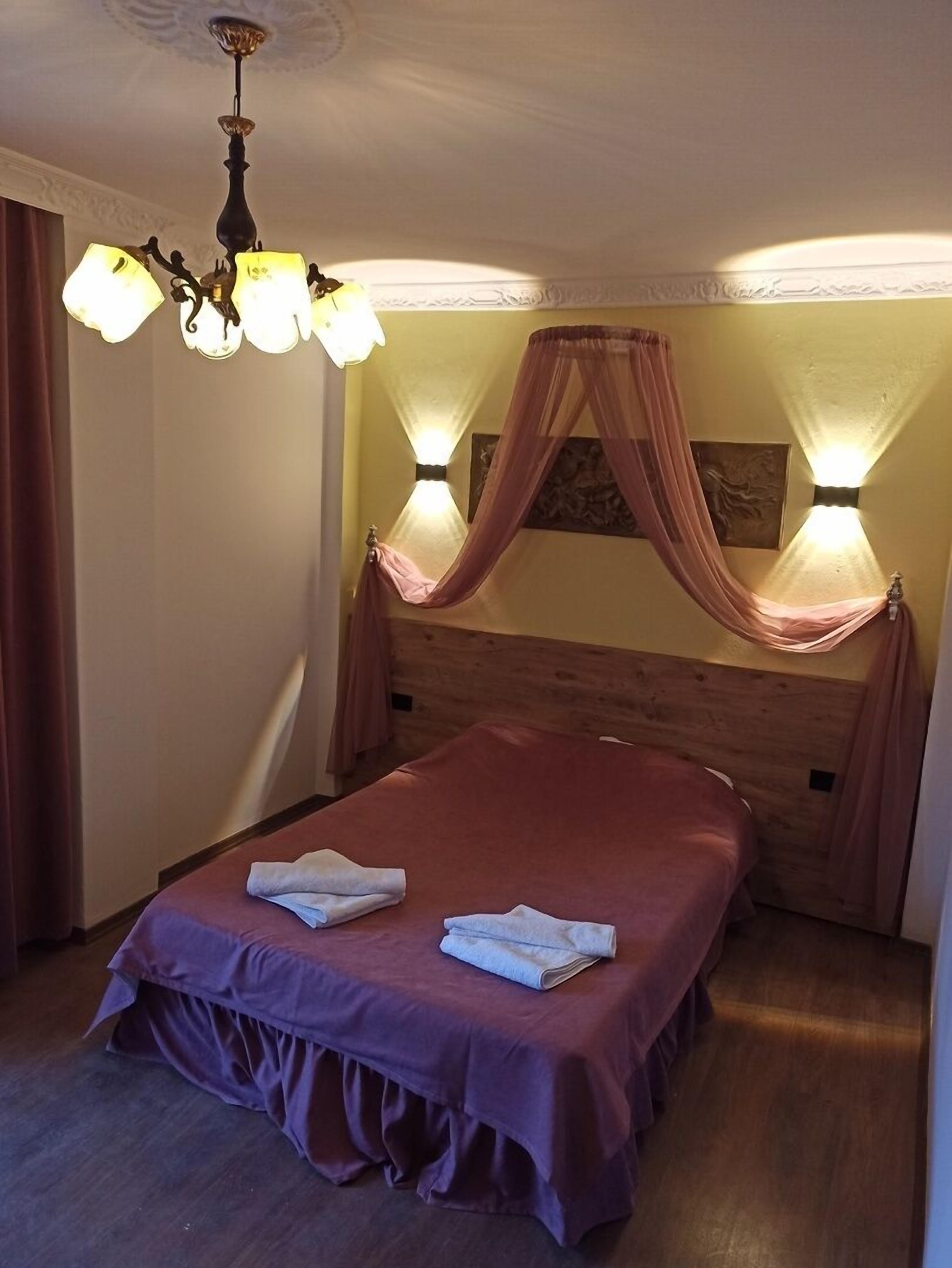 A bedroom with a wooden headboard, a canopy bed, and a chandelier.