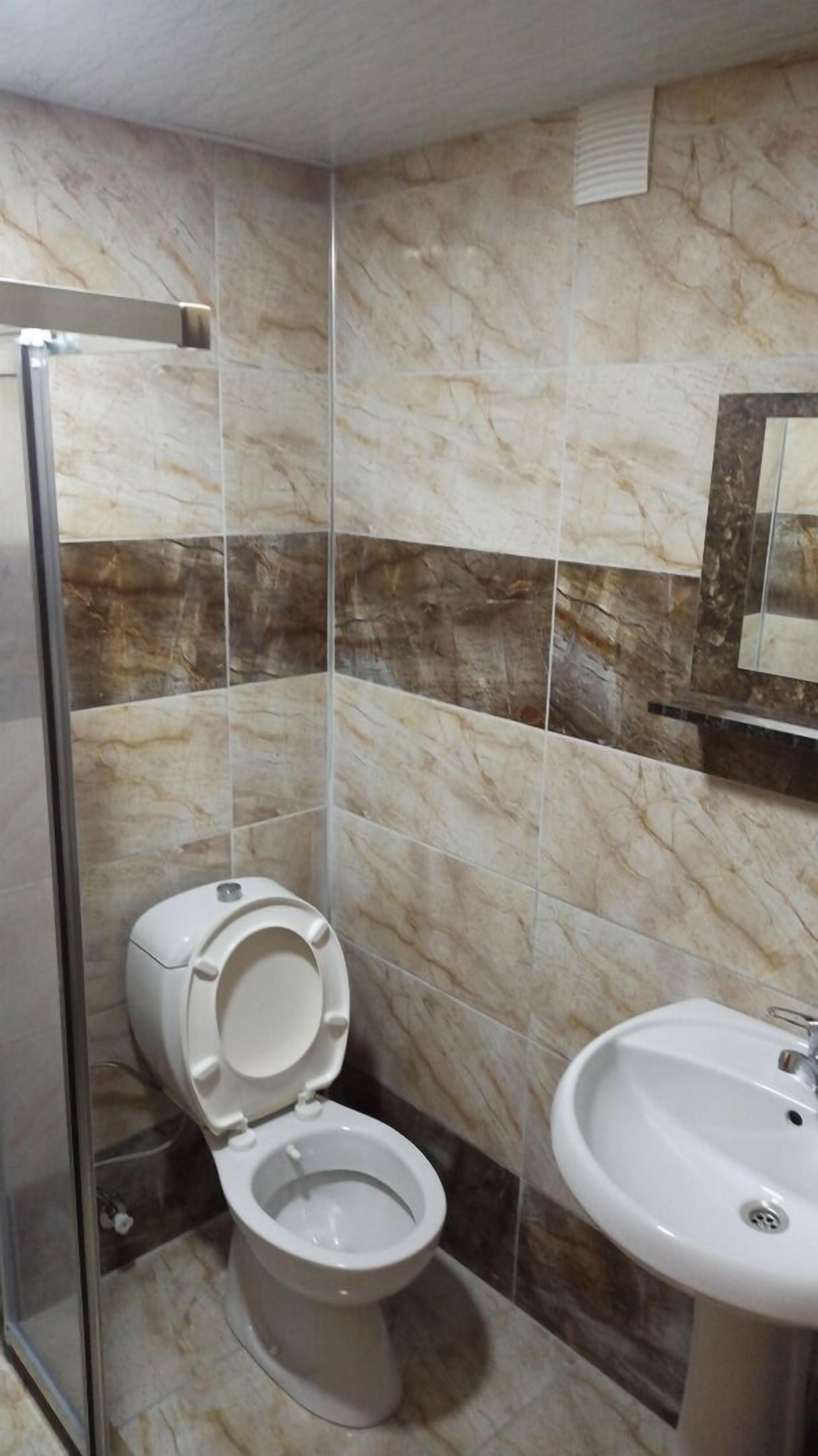 Casa de banho com sanita, lavatório e azulejos de mármore.