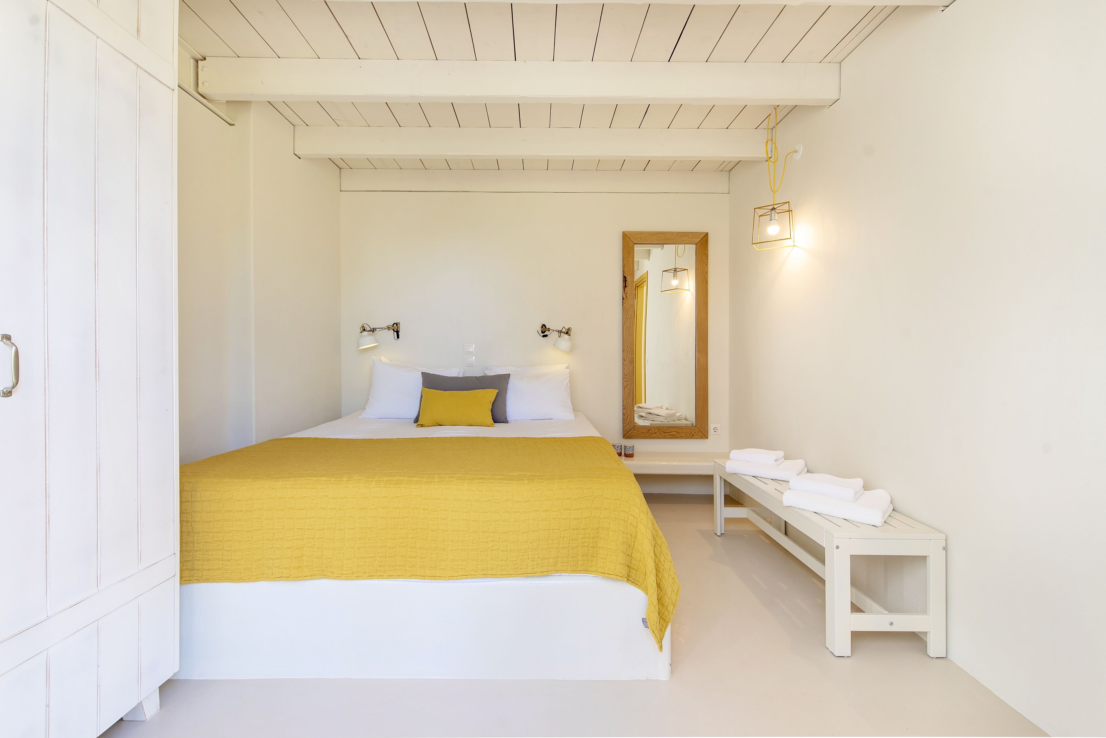 Un dormitorio con cama, mesita de noche y un banco con toallas.