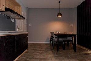 A modern kitchen with a built-in stove, a dining area with a table and chairs, and a pendant light.