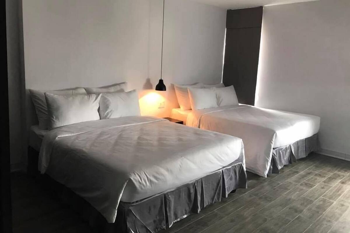 Habitación doble con dos camas, una lámpara colgante y piso de madera.