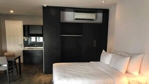 A hotel room with a large bed, a desk, and a kitchenette. - VN HOUSE Beach (Da Nang)