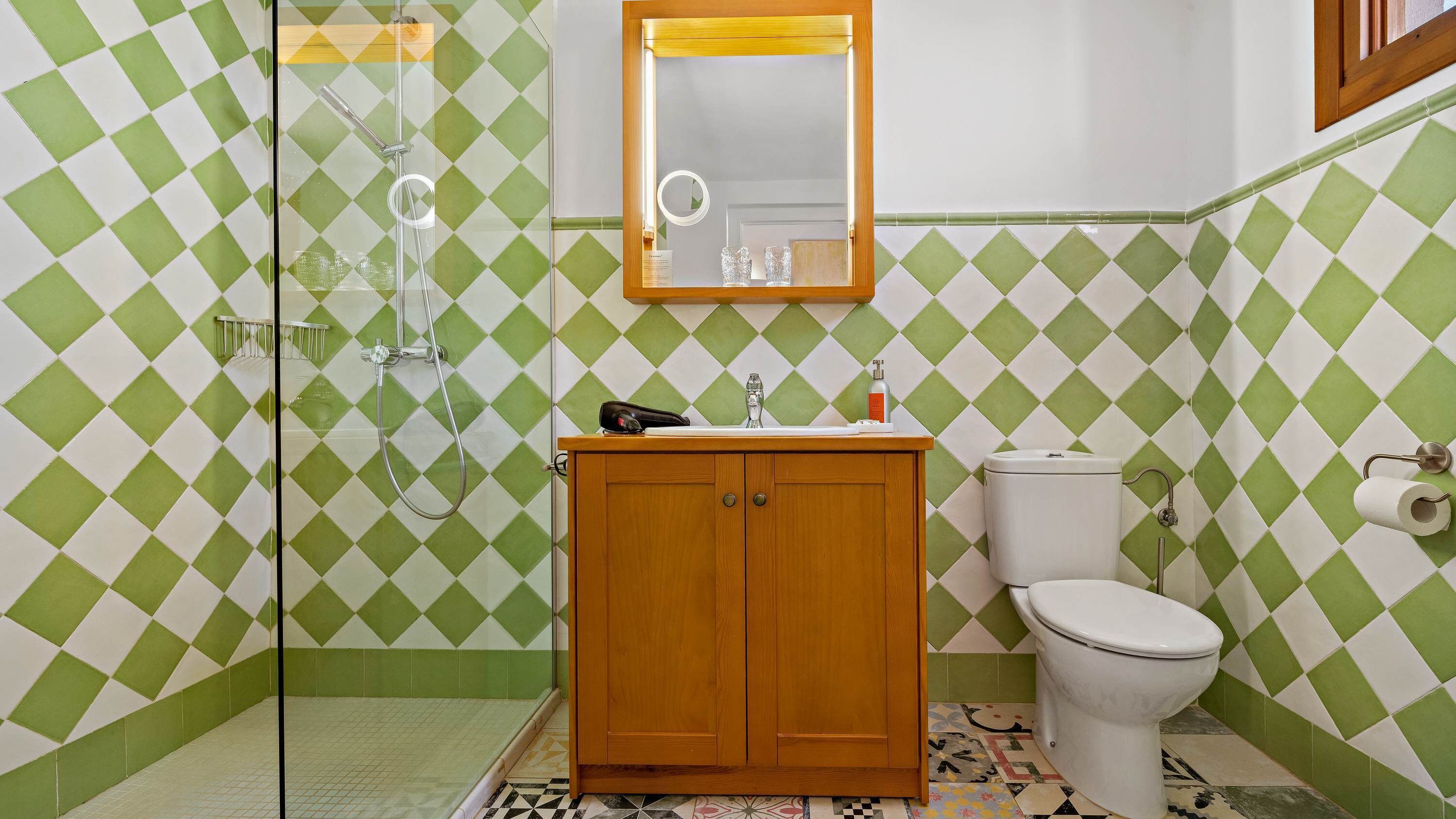 A bathroom with a shower, toilet, and vanity with a mirror.