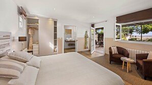 A bedroom with a large bed, a wardrobe, a bathroom, a seating area, and a view of the outdoors. - Boutique Hideaway Cortijo El Sarmiento (Mojacar)