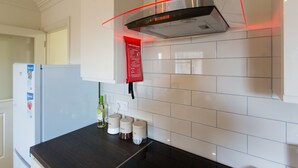 Una cocina moderna con baldosas blancas, extractor de acero inoxidable y encimera oscura.