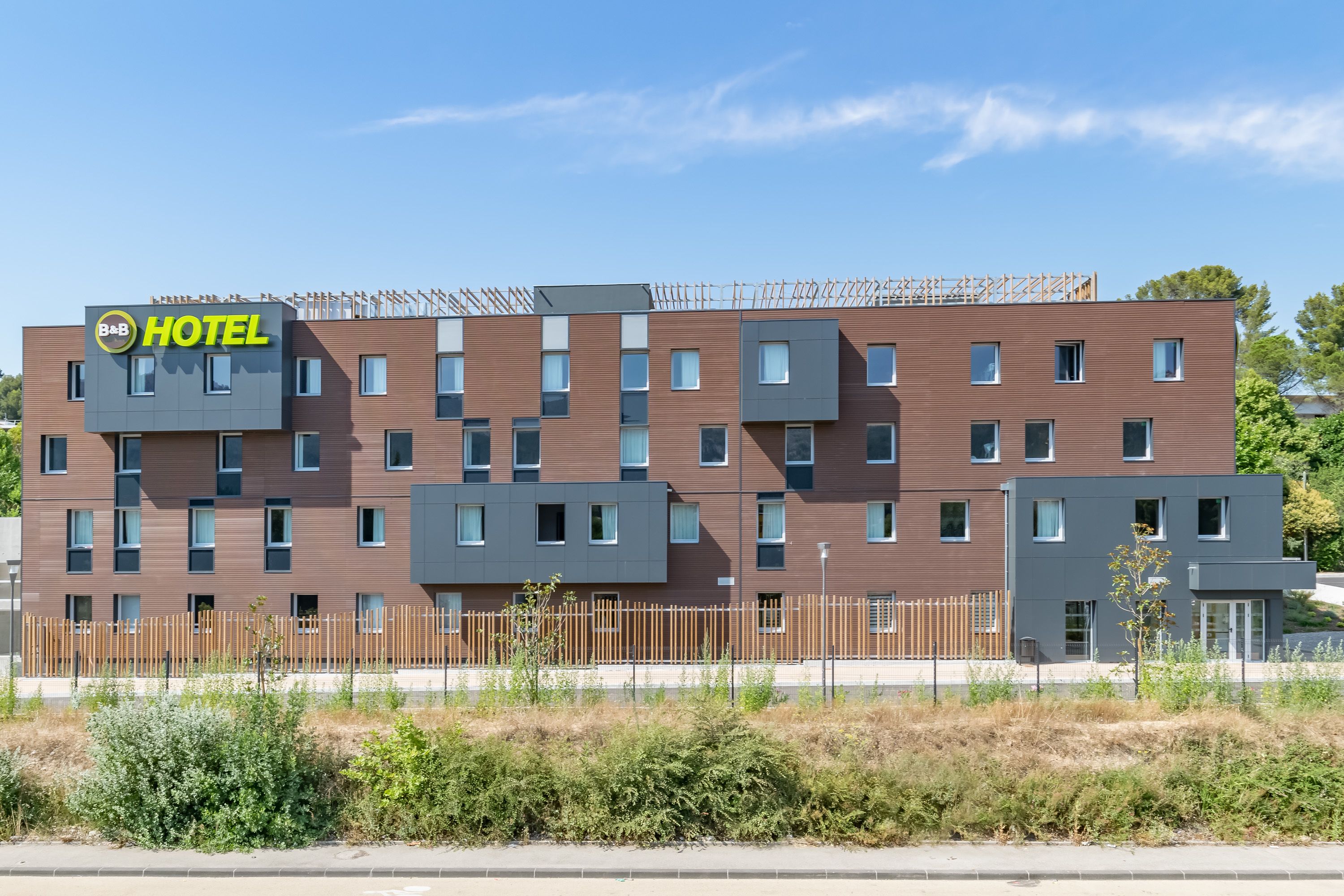 Un moderno edificio de hotel con un letrero que dice 'HOTEL', varias ventanas y una valla de madera al frente.