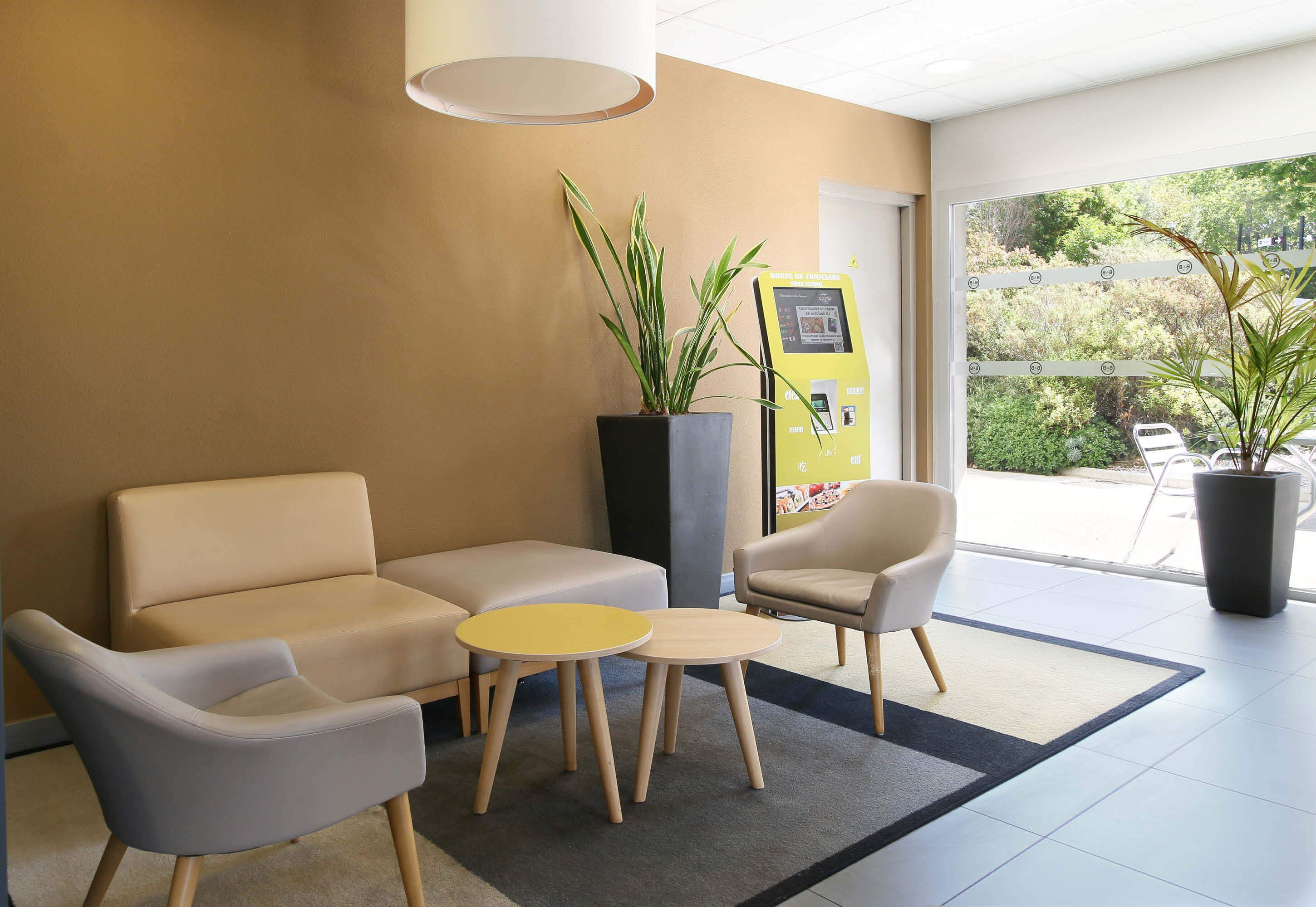Un espace d’accueil comprenant deux canapés, une petite table et un kiosque en libre-service.