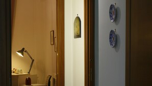 A hallway with a wooden door, a desk with a lamp, and three decorative plates on the wall.