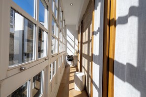 A corridor with large windows, a chair, and a white table. - Casas Reais Boutique (Santiago de Compostela)