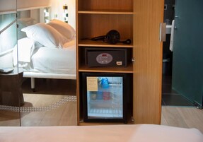 Una habitación de hotel con una cama, un minibar y un refrigerador pequeño.