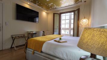 Une chambre d’hôtel avec un lit, un bureau, une chaise, une lampe et une grande fenêtre.