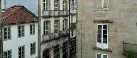Un patio con edificios, una persona caminando y una señal de límite de velocidad de 20 km/h.
