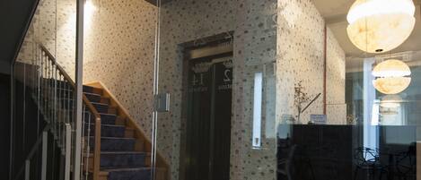 Un interior moderno con una escalera, papel tapiz estampado y un comedor con sillas.