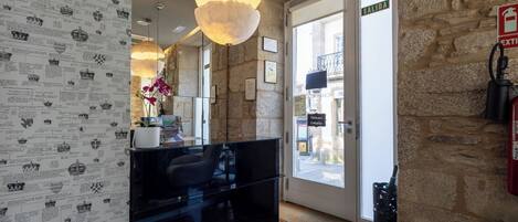 A reception area with a black counter, a large hanging light fixture, stone walls, and a door marked 'SALIDA' with an exit sign.