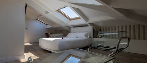 Ein Schlafzimmer im Dachgeschoss mit einem Glastisch, einem Bett und Dachfenstern.