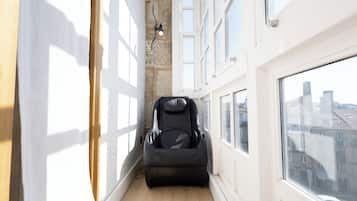 Un couloir étroit avec un fauteuil de massage, de grandes fenêtres et une vue sur la ville.