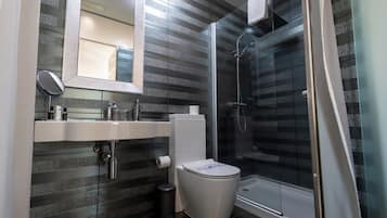 Un baño moderno con cabina de ducha de vidrio, inodoro blanco y lavabo con espejo.