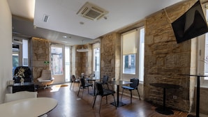 Ein modernes Interieur mit Steinwänden, Holzböden und einer Mischung aus runden und eckigen Tischen mit Stühlen.