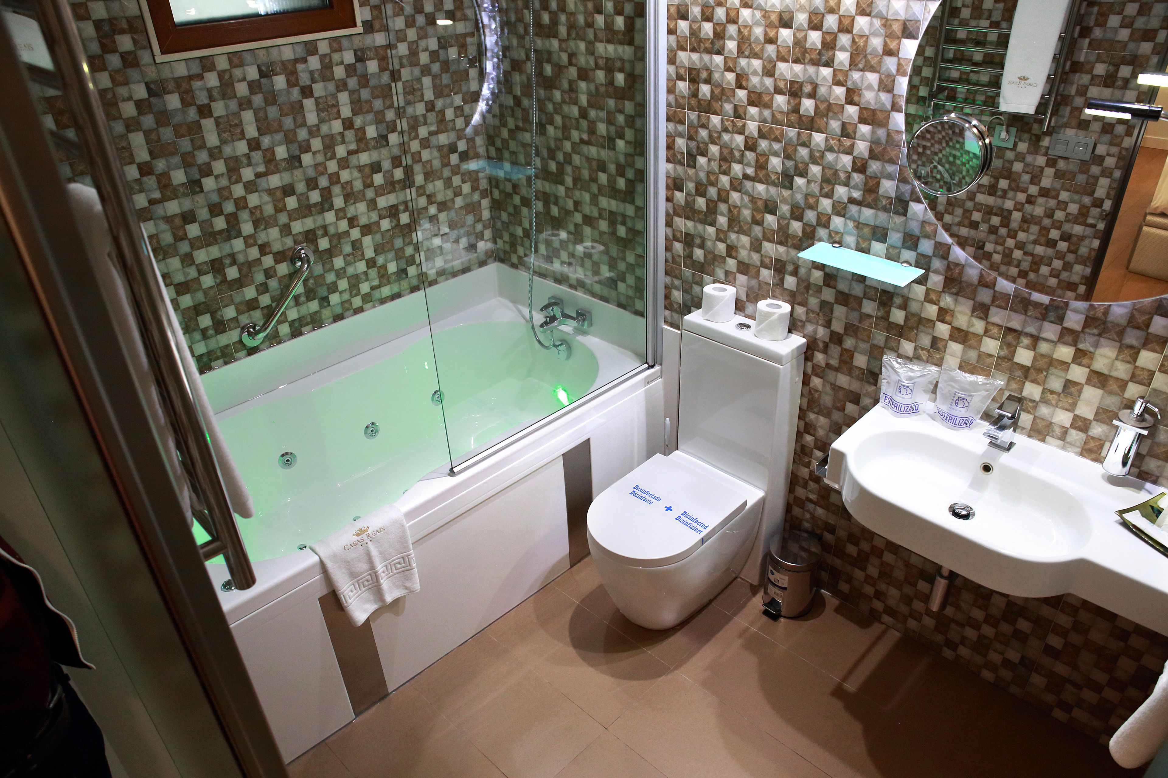 Un baño con ducha envuelta en vidrio, inodoro blanco y lavamanos.