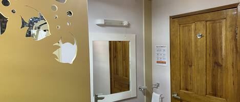 A bathroom with a wooden door, a sink, and a mirror.