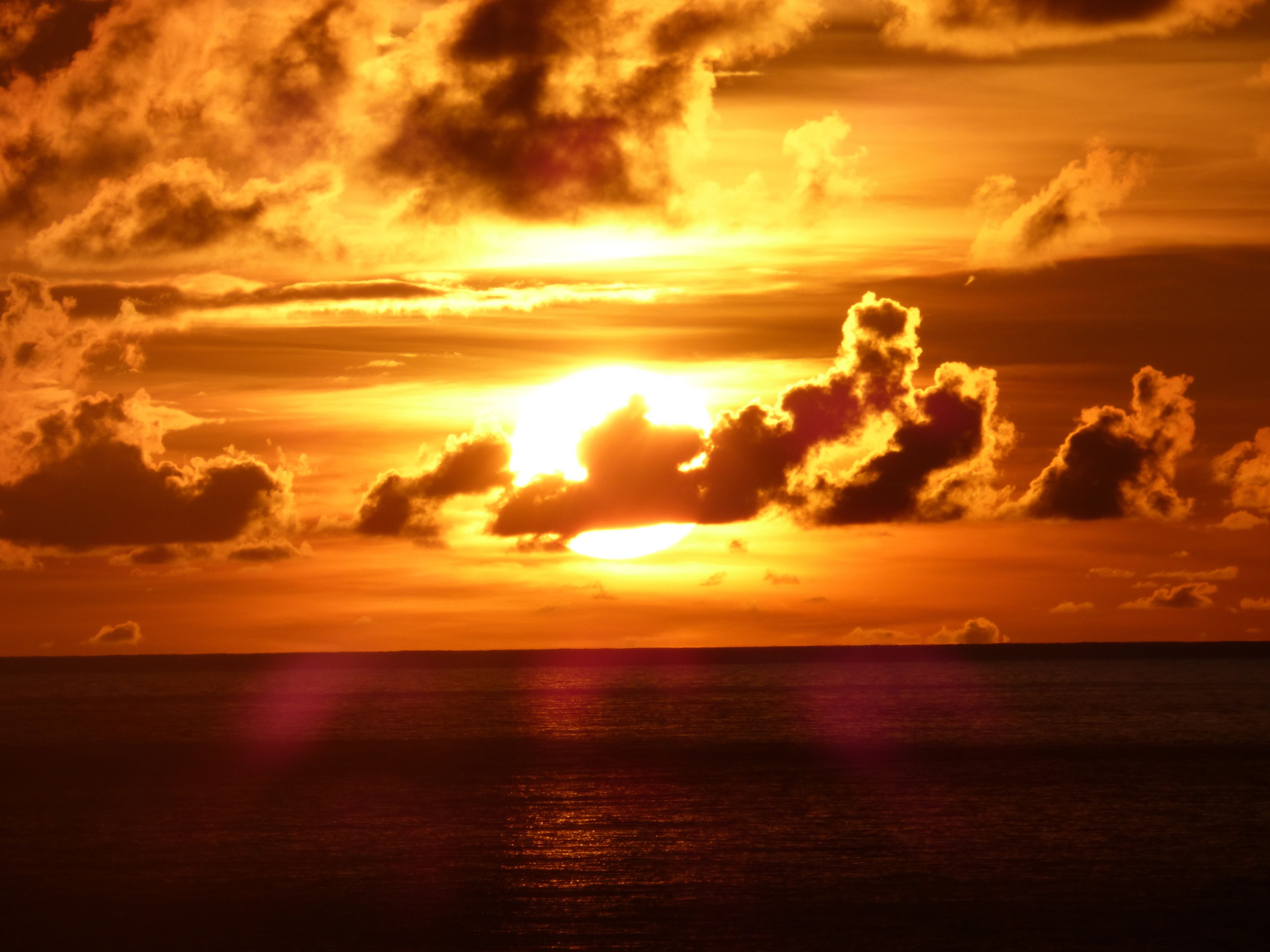 A sunset over the ocean with clouds.