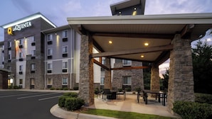 A La Quinta hotel with a covered outdoor seating area, stone pillars, and a parking lot.