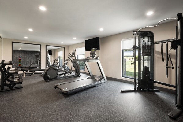 Un gimnasio moderno con cintas de correr, elípticas y equipo de levantamiento de pesas.