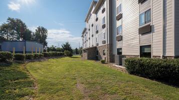 A modern building with a flat roof, multiple windows, and a well-maintained lawn.