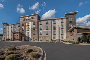 Un hotel a più piani con un evidente cartello 'La Quinta', caratterizzato da un design architettonico moderno con elementi in pietra e legno, e un ingresso coperto.