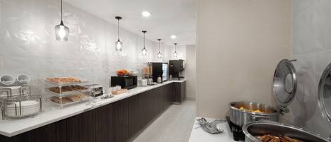 Una cocina moderna con una barra amplia, diferentes estaciones de comida e iluminación colgante.