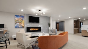 A modern living room with a fireplace, a flat-screen TV, and comfortable seating.