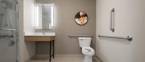 A modern bathroom with a glass shower enclosure, a white sink, a toilet with a grab bar, and a wall-mounted mirror.