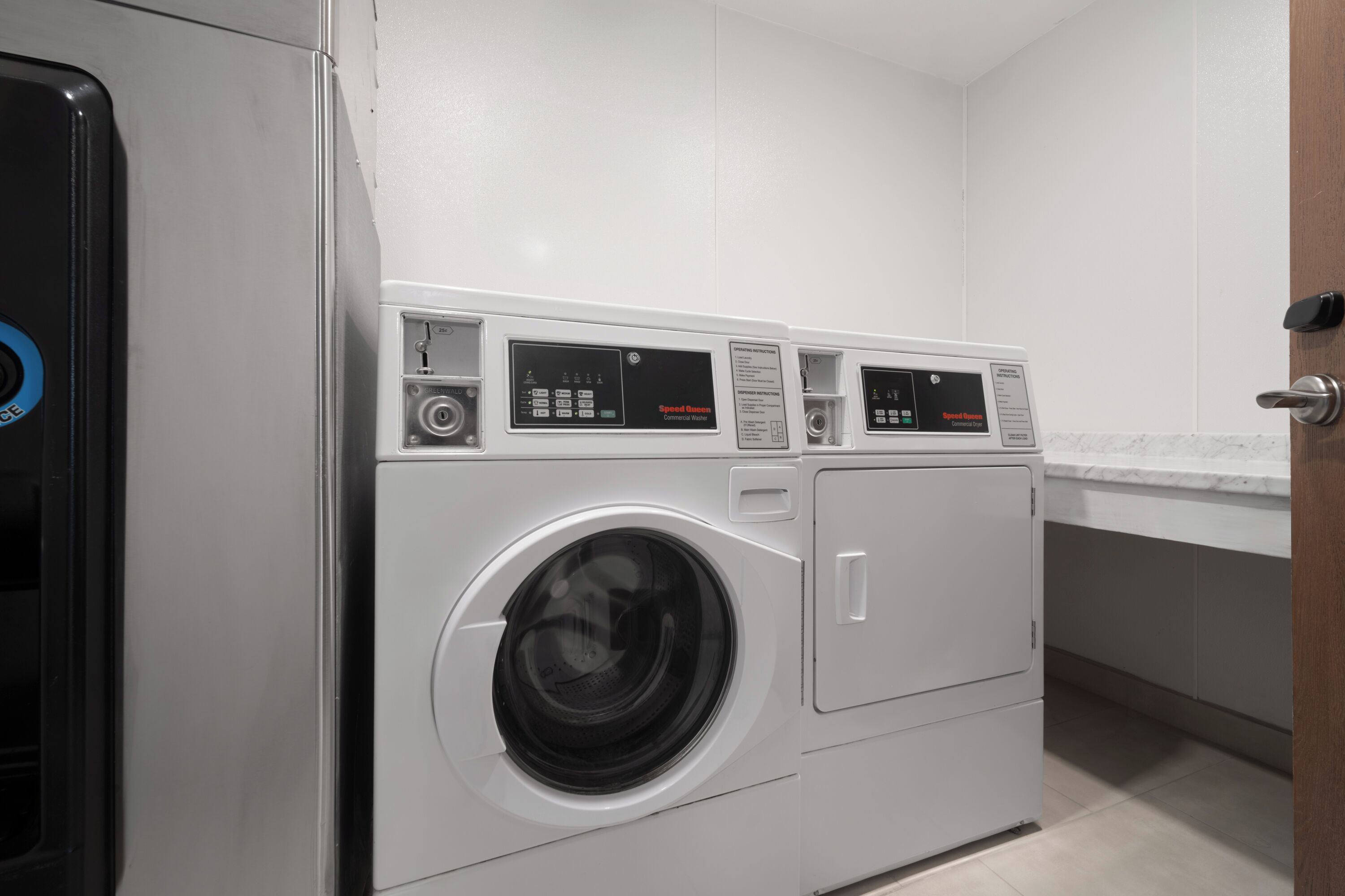 A modern laundry room with two front-loading washing machines and a dryer.