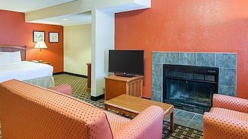 Una habitación de hotel con una cama, un televisor, una chimenea y dos sofás.