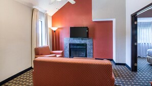 A hotel room with a bed, a fireplace, a television, and a ceiling fan. - Extended Studio Suite Hotel (Bossier City)