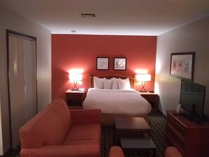 A hotel room with a bed, two bedside tables with lamps, a sofa, a TV, and a wardrobe. - Extended Studio Suite Hotel (Bossier City)