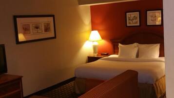 A hotel room with a bed, a nightstand, a lamp, and framed pictures on the wall.