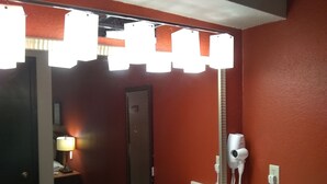 A bathroom with a large mirror, a hairdryer, and a towel dispenser. - Extended Studio Suite Hotel (Bossier City)